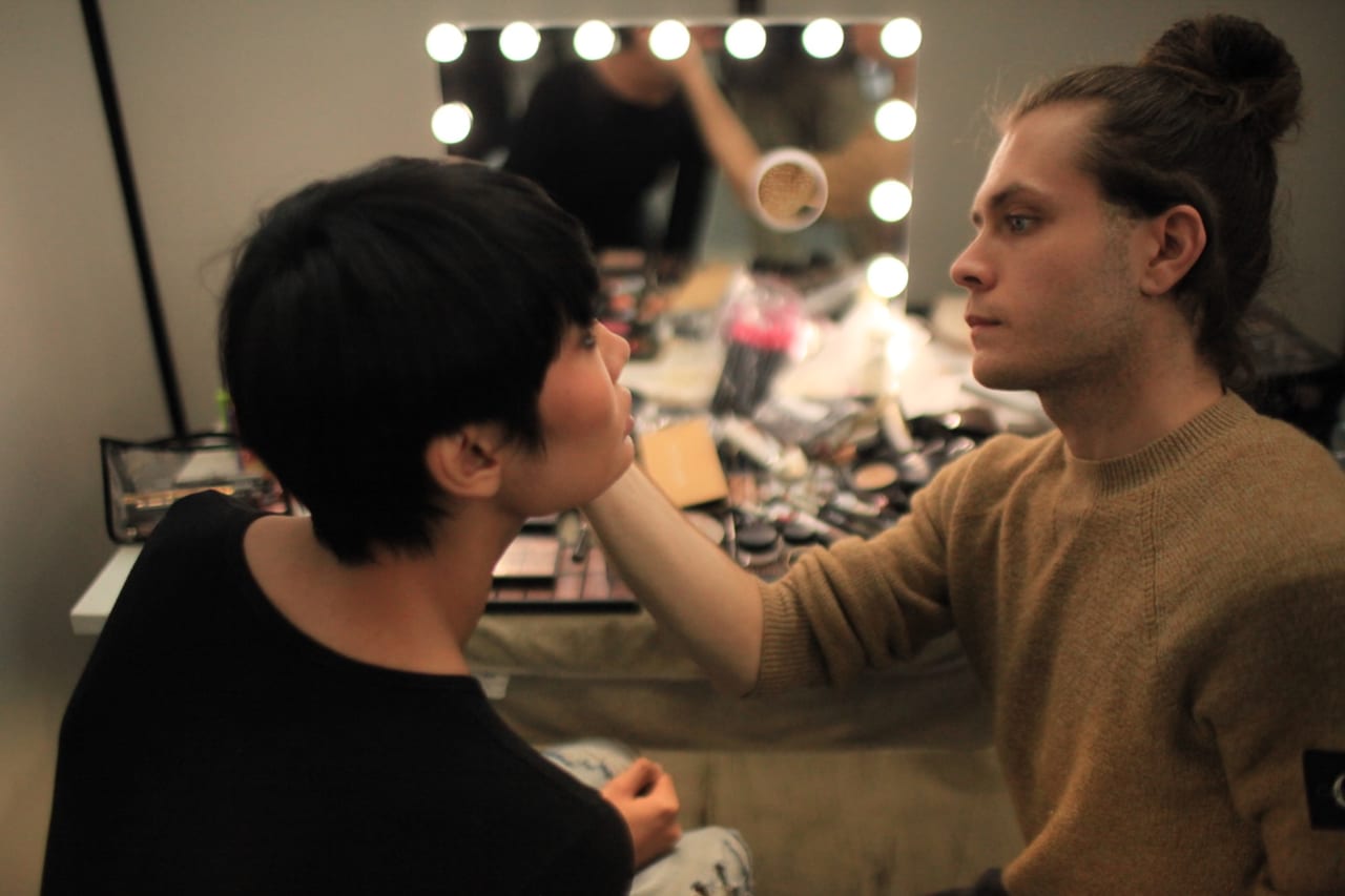 Sessione di trucco a più mani su una modella, vista d’insieme dell’aula.